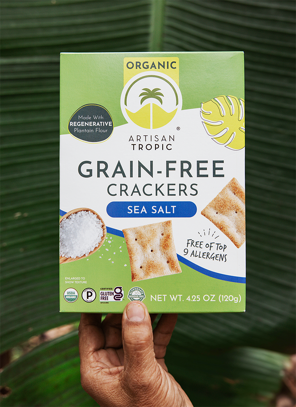 Artisan Tropic Sea Salt Crackers held by a farmer's hand over a plantain leaf