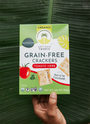 Artisan Tropic Tomato Herb Crackers held by a farmer's hand over a plantain leaf