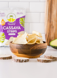 Bowl of Artisan Tropic's 2 oz Sea Salt Cassava Strips with raw cassava and an avocado slice in the background